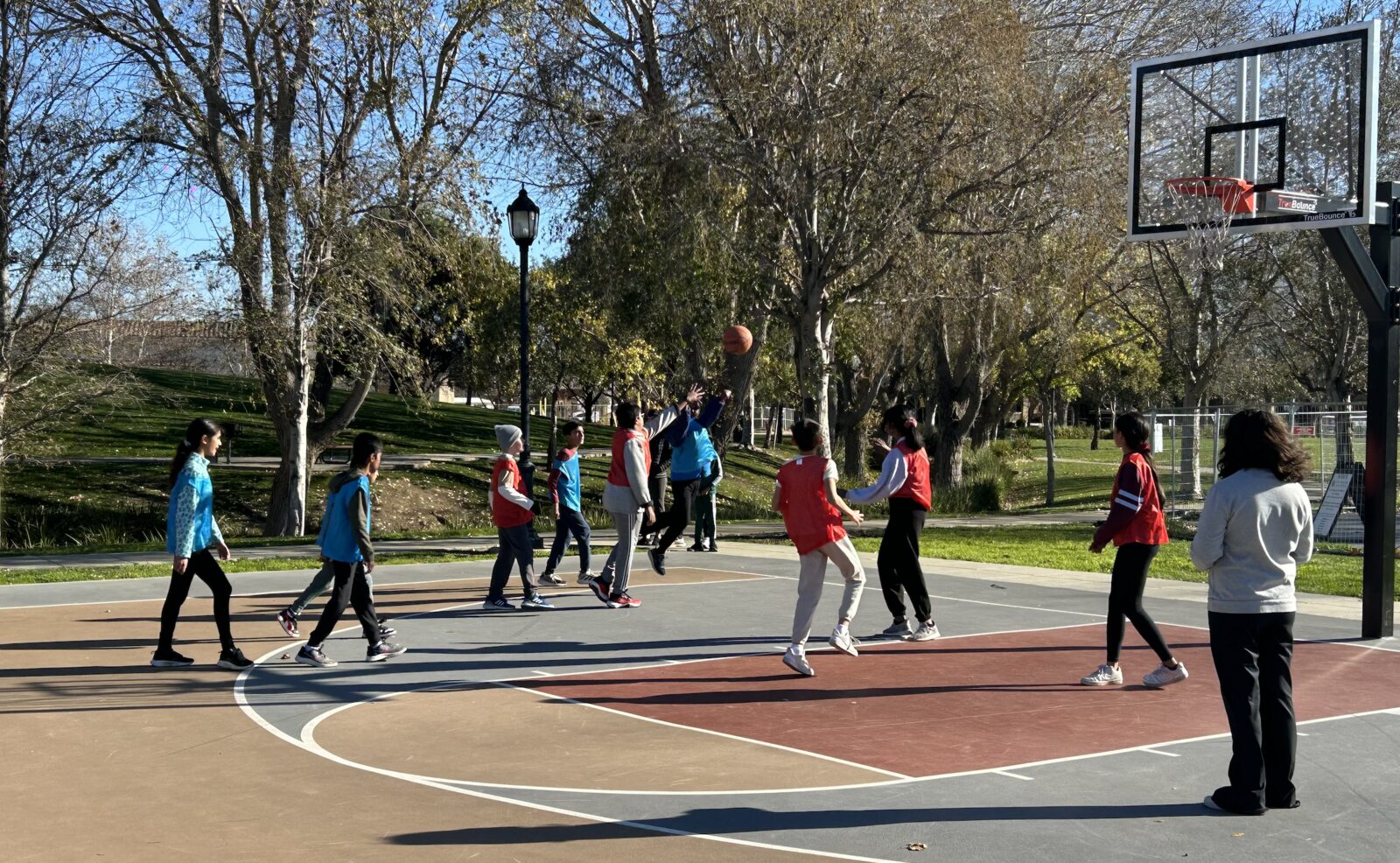 Players in a scrimmage reaching for a rebound near the hoop